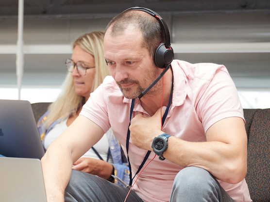 A man wearing headphones in front of a computer in an office.